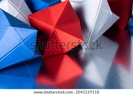 Several geometric diamond-shaped different colored paper figures on a reflective surface. Elegant background providing concept of parts of a whole, business, team, products, etc.
