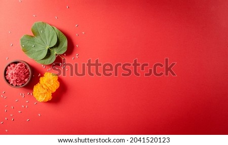 Happy Dussehra. Yellow flowers, green leaf and rice on red background. Dussehra Indian Festival concept. Royalty-Free Stock Photo #2041520123