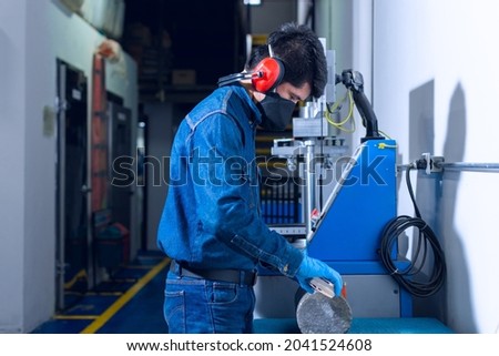 Male industrial worker with protective mask and hearing protectors measuring a concrete cylinder on test laboratory