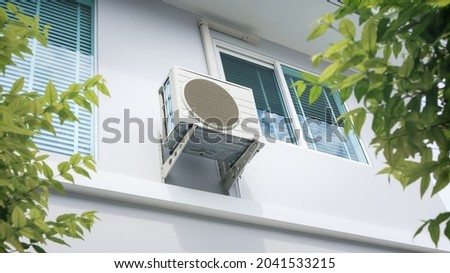 Condenser unit or compressor outside home or residential building. Unit of central air conditioner (AC) or heating ventilation air conditioning system (HVAC). Electric fan and refrigerant pump inside. Royalty-Free Stock Photo #2041533215