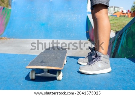 Close up of legs of a child on a skateboard about to start enjoying a skateboarders' park . High quality photo