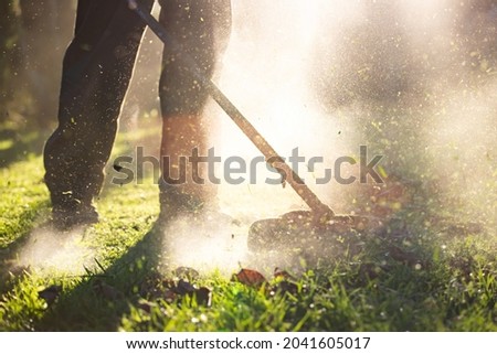 Mowing the grass with a lawn mower. Garden work concept background.
