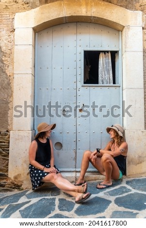 Girlfriends in summer enjoying the holidays. Caucasian girls with hats smiling sitting in next to a door enjoying the heat in the holidays