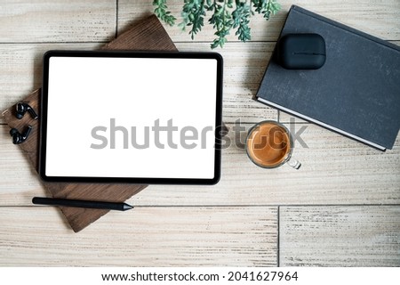 Top view blank screen tablet with gadget and coffee cup on wooden background.