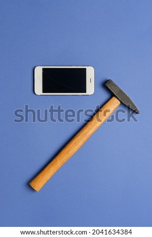 Mobile phone and hammer on color background