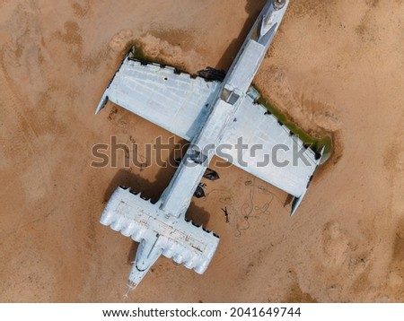 two people a boy and his dad are lying on the sand next to an ecroplane plane drone point of view