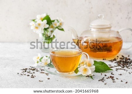 Composition with cup of jasmine tea and flowers on light background Royalty-Free Stock Photo #2041665968