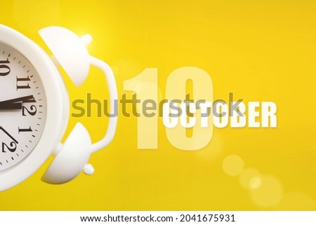 October 10th. Day 10 of month, Calendar date. White alarm clock on yellow background with calendar day. Autumn month, day of the year concept