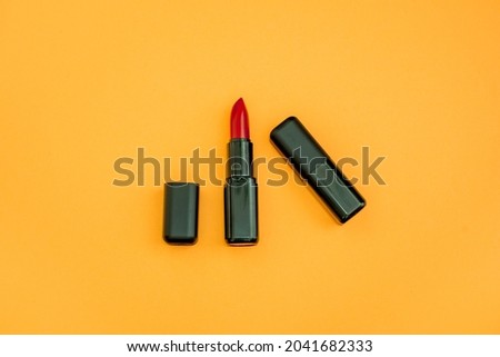 Fashion cosmetics photo of red lipsticks in a black packaging on a orange background 