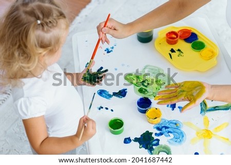 Toddler girl painting at home. Happy creative child spending time with fun and joy. Learning colours