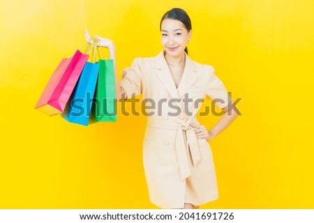 Portrait beautiful young asian woman smile with shopping bag on color background