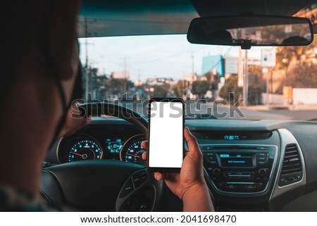 uber driver showing the phone while driving wearing a facemask Royalty-Free Stock Photo #2041698470
