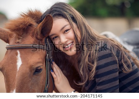 Close-up portrait of Asian girl hugging her bay pony