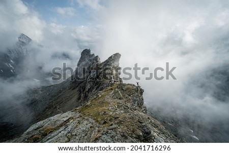 Soft focus. Dramatic fog among giant rocky mountains. Ghostly atmospheric view to big cliff in cloudy sky. Low clouds and beautiful rockies. Minimalist scenery i mysterious place.

