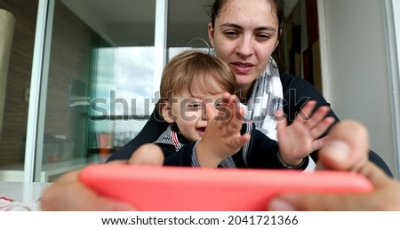 Little boy watching online content on smartphone. Baby on mother lap holding cellphone close-up
