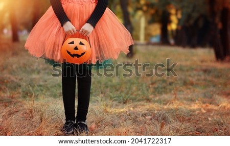 Little girl in witch costume with a pumpkin bucket . Kid having fun at Halloween trick or treat. Kids trick or treating.