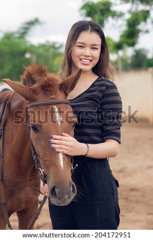 Portrait of cheerful girl stroking brown pony
