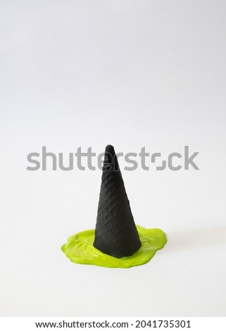 Halloween inspiration design idea.witch black hat made of ice cream cone melting in green strange mixture.spooky concept