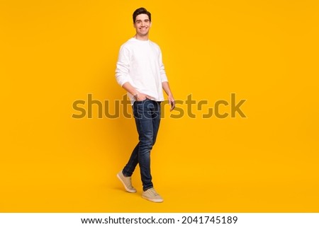Full size profile photo of funny brunet young guy go wear shirt jeans sneakers isolated on yellow color background