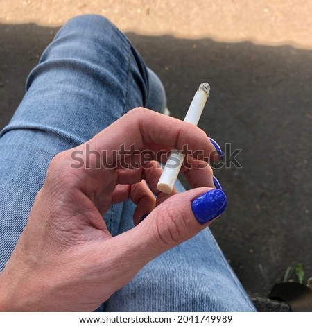 Macro photo cigarette in hand. Stock photo woman smokes a cigarette