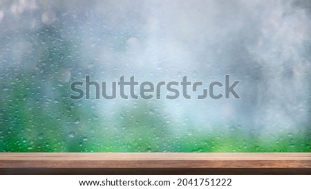 The wooden tabletop on a blur window background with smoke float up with rain , can be used for display or montage your products, Morning light, blurred image