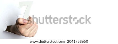 Female hand holds the number seven white isolated background. Copy Space.