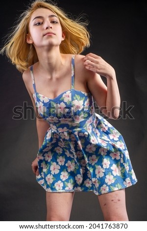 A girl in a short sarafan with a floral print in blue.