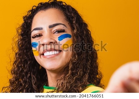 Brazilian fan with painted face taking a selfie