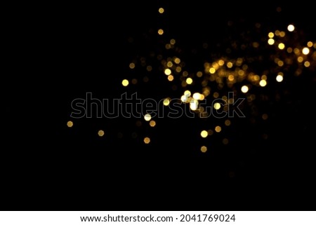 Golden blurred bokeh lights on black background. Glitter sparkle stars for celebrate. Overlay for your design Royalty-Free Stock Photo #2041769024