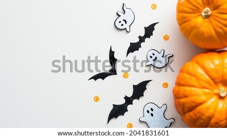 Happy Halloween holiday flat lay composition with cute decorations. Top view pumpkins, ghosts, bats on white background.
