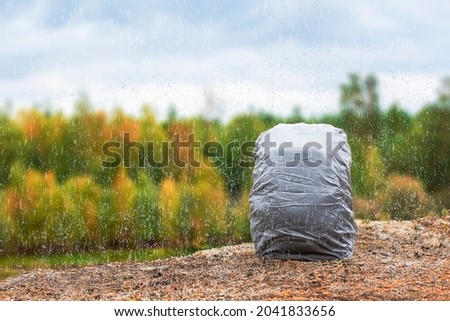 Matching backpack in rain cover on the taiga shore. Inventory for the campaign Royalty-Free Stock Photo #2041833656