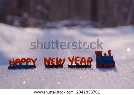 A toy train and a happy new year sign on the snow background.