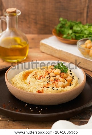 Chickpea hummus dip in bowl on wooden table. Copy space, selective focus. Vegetatian healthy food concept.