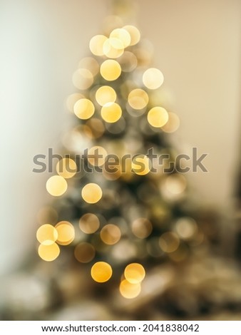 Cozy blur bokeh flat apartment room with green Christmas Tree gifts presents garlands, candles decorated interior New Year beautiful living room in the evening, lights glowing
