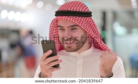 Portrait of Excited Arab Businessman Celebrating Success on Smartphone