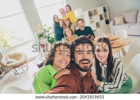 Photo of friendly sweet family eating holiday turkey smiling sitting table hugging recording self video indoors house room