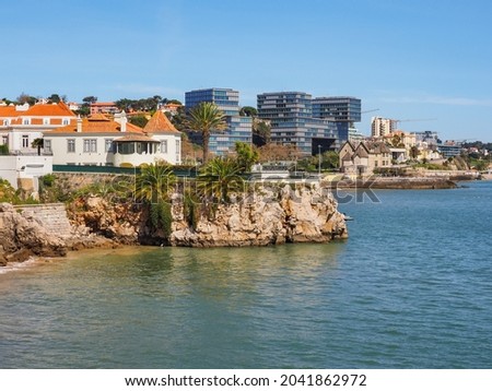 Rocky Atlantic ocean coast. Beautiful landscape and scenic seaside next to public beach 'Praia da Rainha' in the Cascais, Portugal. On the steep cliffs standing old and modern houses. Royalty-Free Stock Photo #2041862972