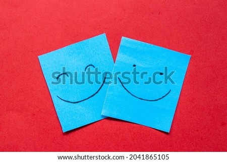 Smiling faces drawn on paper. Happiness, love and friendship concept. Color stickers with happy face on red background.
