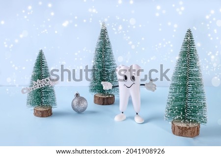 cartoon model of a tooth, Christmas trees with a ball and the inscription merry Christmas on a blue background