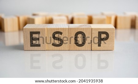 esop - employee stock ownership plan - word of wooden blocks with letters on a gray background. Reflection of the caption on the mirrored surface of the table. Selective focus.