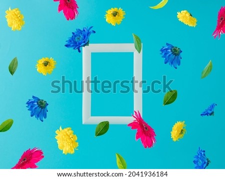 White frame with colorful spring flowers flying on a blue background. Positive news, thinking and energy concept. Optimistic future, mood and atitude.  Advertisement idea. Surreal authentic concept.