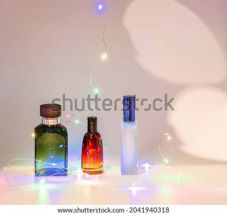 THREE BOTTLES OF PERFUME AND LED LIGHTS ON A WHITE BACKGROUND Giving a perfume says you care about that person Few gifts are more universal when it comes to ages