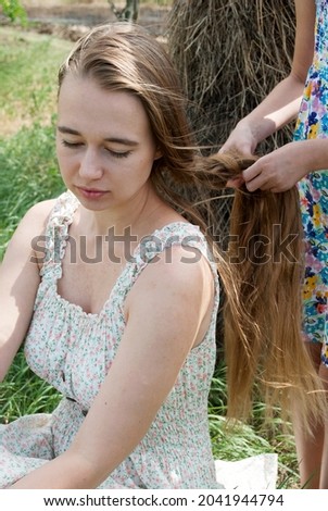 Family photo.The girl weaves a braid for her mother, sister. Children's hands braiding long hair. 