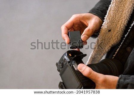 Close-up photo of photographer inserting battery to the camera before shootout. Battery replacement in the modern camera