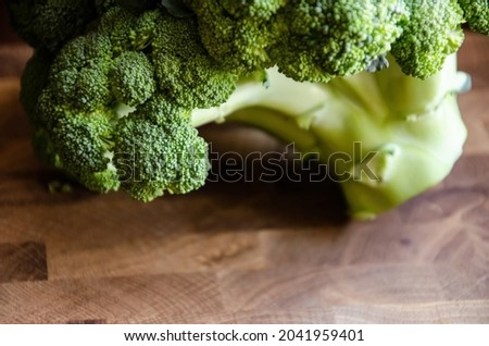 Close-up broccoli inflorescences on wooden blurred background with copy space. Top view. Fresh head of broccoli lies on a wooden brown table. Fresh vegetable concept. Cruciferous plant.