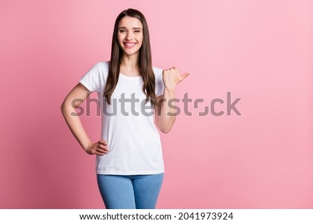 Photo portrait young woman pointing copyspace thumb isolated pastel pink color background