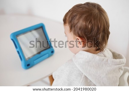 Happy little boy playing game on digital tablet at home. Portrait of a child at home watching cartoon on the tablet. Modern kid and education technology.