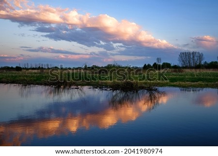 A hot summer evening, the smooth surface of a flood pond, a cloud and its reflection formed an arrow. A calm mirror picture for meditation. Great for wallpaper.