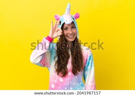 Girl with unicorn pajamas over isolated background showing ok sign with fingers