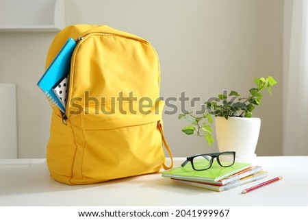Yellow backpack and stack of notepads on table home. School supplies. Back to school concept. Educational design objects. Home studies.Schoolbag. Royalty-Free Stock Photo #2041999967